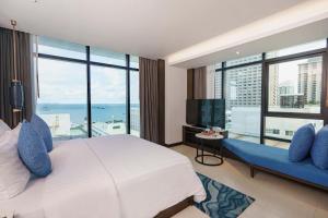 a hotel room with a large bed and a large window at Mytt Beach Hotel - SHA Extra Plus in Pattaya Central