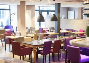 een restaurant met tafels en stoelen en paarse stoelen bij Campanile Dijon Centre - Gare in Dijon