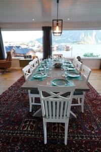 tavolo da pranzo con sedie bianche e ampia finestra di Lofoten panoramic luxury home with sauna a Moskenes