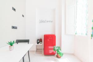 um frigorífico vermelho num quarto branco com uma mesa em Linee Moderne Apt - Wifi - AC em Cagliari
