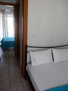 a bedroom with a bed with white pillows and a window at Dasea Houses in Ormos Panagias