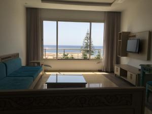 a living room with a blue couch and a large window at Arabesque Style - 2 appartements in Kelibia