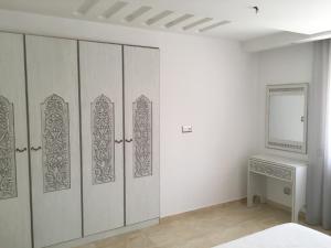 a room with white cabinets and a table and a mirror at Arabesque Style - 2 appartements in Kelibia