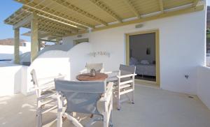 a patio with a table and chairs and a bed at Diasino Apartments and Car Rental in Katapola