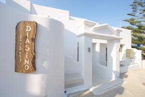 a white house with a sign on the side of it at Diasino Apartments and Car Rental in Katapola