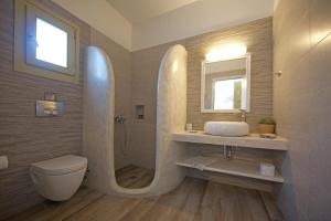 a bathroom with a sink and a toilet and a mirror at Diasino Apartments and Car Rental in Katapola