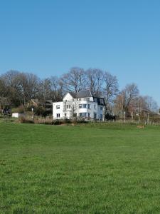 una gran casa blanca en un campo de hierba en La Roseraie en Stavelot