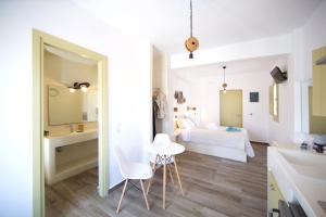 a white bedroom with a bed and a table and chairs at Diasino Apartments and Car Rental in Katapola