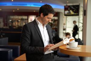 Un uomo seduto a un tavolo che legge un libro di Ramada Encore By Wyndham Tangier a Tangeri