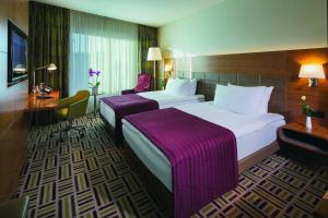 a hotel room with two beds and two lamps at Movenpick Hotel Ankara in Ankara