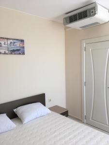 Un dormitorio con una cama blanca y un ventilador. en Vase Apartments, en Ravda
