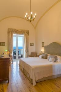 a bedroom with a bed and a desk and a window at Grand Hotel Excelsior Vittoria in Sorrento