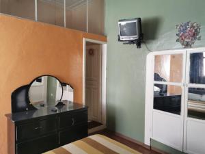 baño con tocador, espejo y TV en Hotel Rosim, en Latacunga