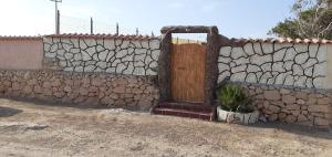 a stone wall with a wooden door and a plant at La Casa Dei Delfini in Lampedusa