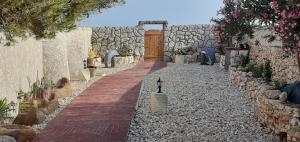 a walkway with a stone wall and a wooden door at La Casa Dei Delfini in Lampedusa