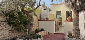 a house with a tree and a stone wall at La Casa Dei Delfini in Lampedusa