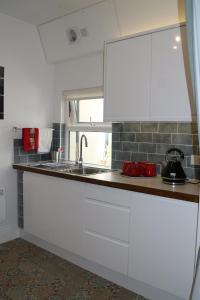 uma cozinha com armários brancos e um lavatório em The Holt em Llangollen