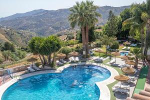 a pool at a resort with palm trees and mountains at Hotel y Bungalows Balcón de Competa in Cómpeta