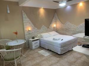 a bedroom with a bed and a table and a desk at Pousada Nascente Pequena in Guapimirim