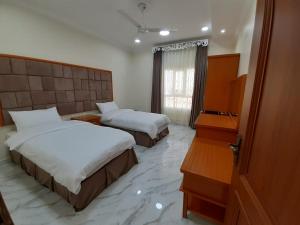 a hotel room with two beds and a piano at AL JOOD HOTEL APARTMENT in Ḩilf