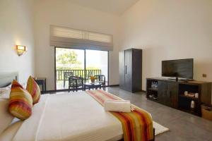a bedroom with a large bed and a flat screen tv at Grand Tamarind Lake in Kataragama