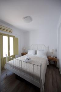 a bedroom with a large bed with white sheets at Diasino Apartments and Car Rental in Katapola