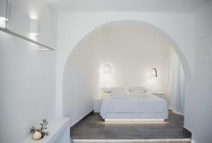 um quarto branco com uma cama num arco em Manthos Place 2 em Mylopotas