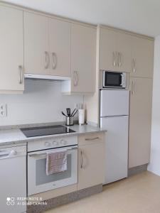 a kitchen with white cabinets and a stove and refrigerator at Piso de alquiler en Tapia de Casariego in Tapia de Casariego