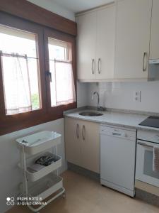 una cocina con armarios blancos y fregadero en Piso de alquiler en Tapia de Casariego, en Tapia de Casariego