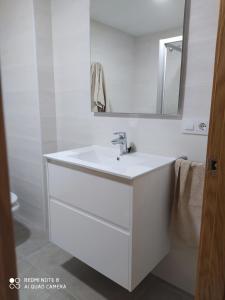 La salle de bains blanche est pourvue d'un lavabo et d'un miroir. dans l'établissement Piso de alquiler en Tapia de Casariego, à Tapia de Casariego