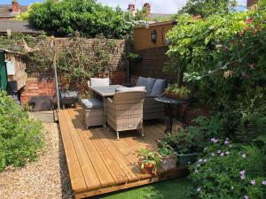a wooden deck with a table and chairs in a garden at 202 Guesthouse in Lincoln