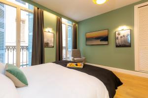 a bedroom with a bed with a chair and windows at Les appartements chics du Vieux-Port in Marseille