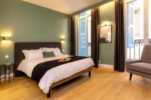 a bedroom with a bed and a chair and windows at Les appartements chics du Vieux-Port in Marseille