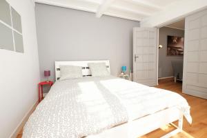 a white bedroom with a large white bed in it at Escale de 80 m2 avec cour et parking in Lille