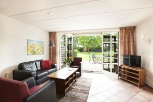 uma sala de estar com um sofá e uma televisão em Vakantiehuisjes Op De Horst em Groesbeek