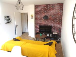 - un salon avec un canapé jaune et un mur en briques dans l'établissement Appartement Lille/1ch/stationnement gratuit, à Lille