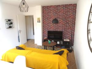 uma sala de estar com um sofá amarelo e uma parede de tijolos em Appartement Lille/1ch/stationnement gratuit em Lille
