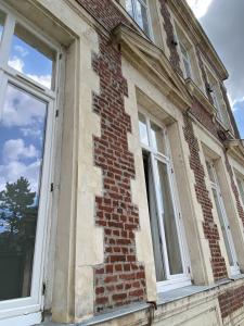 um antigo edifício de tijolos com duas janelas em Trankil-Apparts Centre 2 em Saint-Quentin
