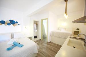 a white room with two beds and a sink at Diasino Apartments and Car Rental in Katapola
