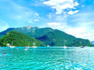 a group of people in the water with mountains in the background at 4* + 5* Luxury Apartments in Sankt Gilgen