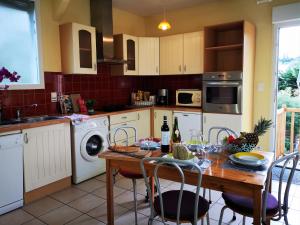 cocina con mesa de madera con sillas y comedor en Gîtes "Le Clos de La Baie", en Paimpol