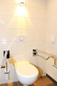
a white toilet sitting in a bathroom next to a sink at Hotel & Gasthaus DAS RÖHRL Straubing in Straubing
