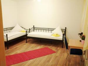 two beds in a room with a red rug at Maffei Apartments in Nuremberg