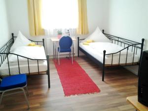 two beds in a room with a red rug at Maffei Apartments in Nürnberg