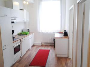 a kitchen with white cabinets and a red rug at Maffei Apartments in Nuremberg