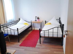 two beds in a room with a table and a red rug at Maffei Apartments in Nuremberg +18 photos