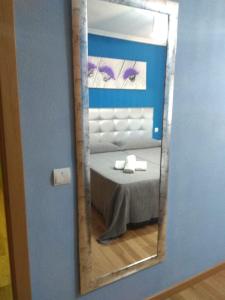 a mirror in a room with a bed with a table at Lomar in Seseña