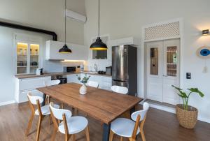 cocina con mesa de madera y sillas blancas en Letty's House - Old Town Luxury Mansion, en Rodas