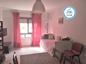 a bedroom with a bed and a window with pink curtains at Apartamento Familiar Lisboa Taguspark in São Marcos