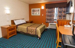 a small hotel room with a bed and a desk at Cambridge Inn in Cambridge